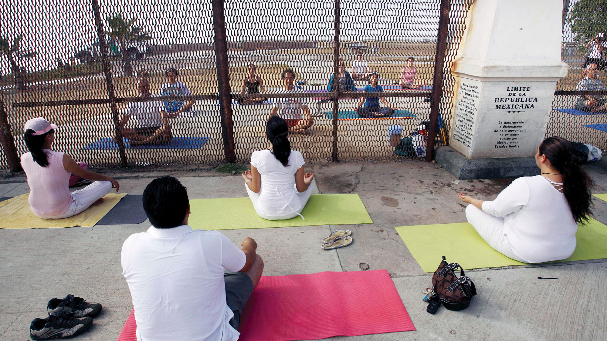 Practitioners of “yoga without borders” meet on opposite sides  of the Tijuana–San Diego border fence. (Photo by Guillermo Arias/Associated Press.)