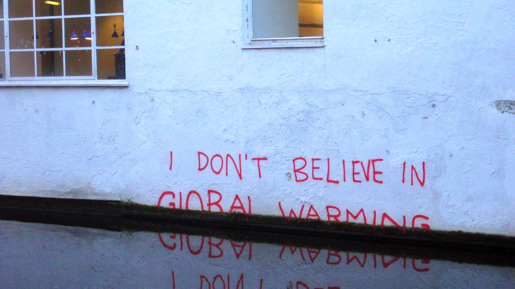 Climate change may lead to rising water levels, despite denials: a satiric piece of graffiti reads "I don't believe in global warming" as it disappears underwater. (Photo by Matt Brown.)