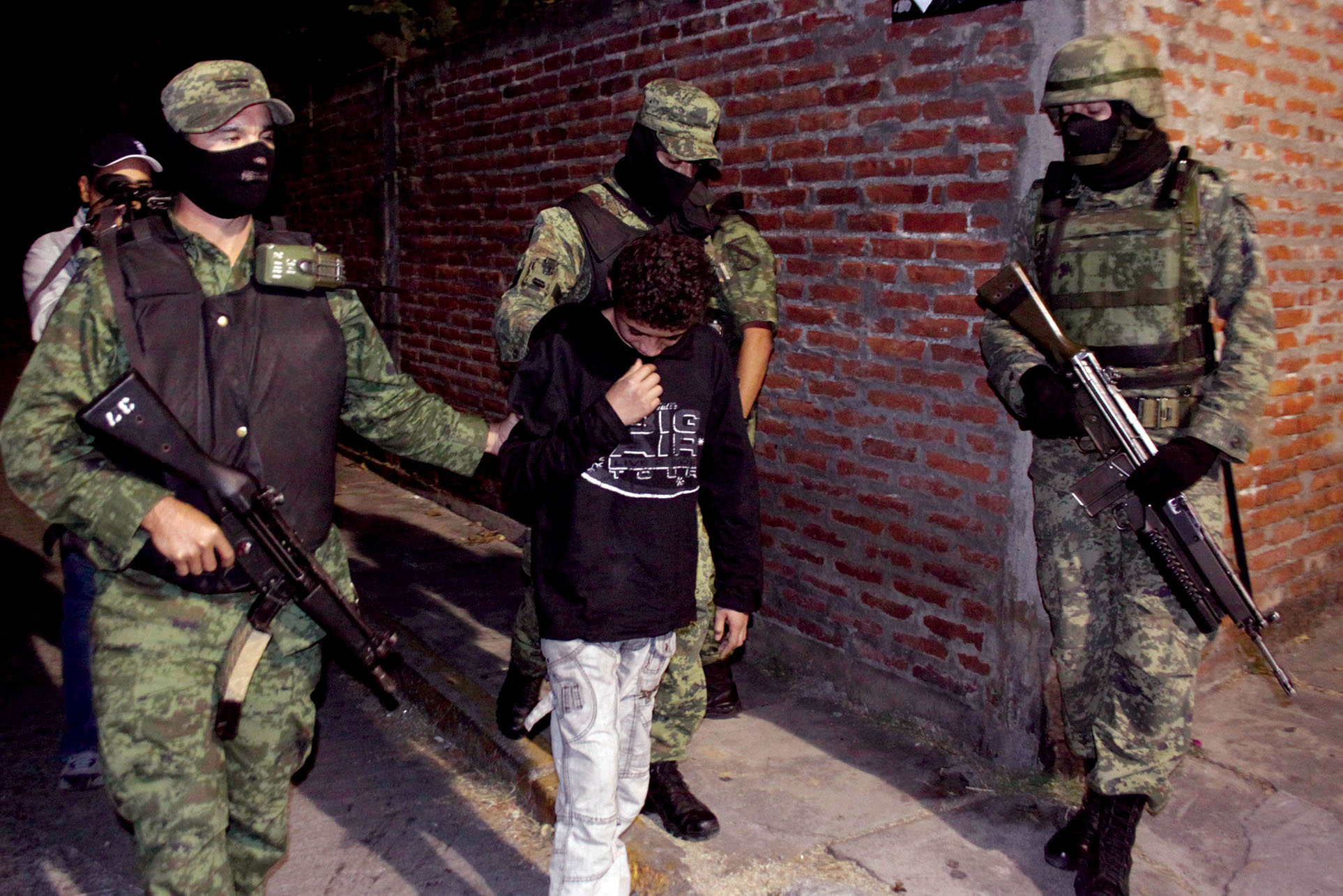 Soldiers transport a 14-year-old U.S. citizen accused of four beheadings in the streets in Mexico. (Photo by Antonio Sierra/Associated Press.)