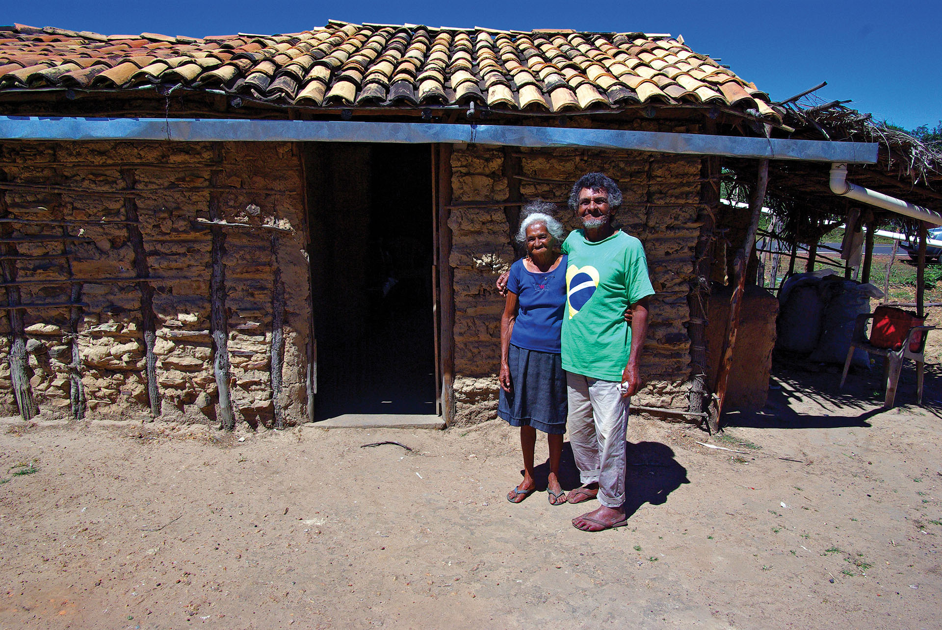 People like this elderly couple standing in front of their home are the beneficiaries of some of Brazil’s social programs. (Photo by Otávio Nogueira.)