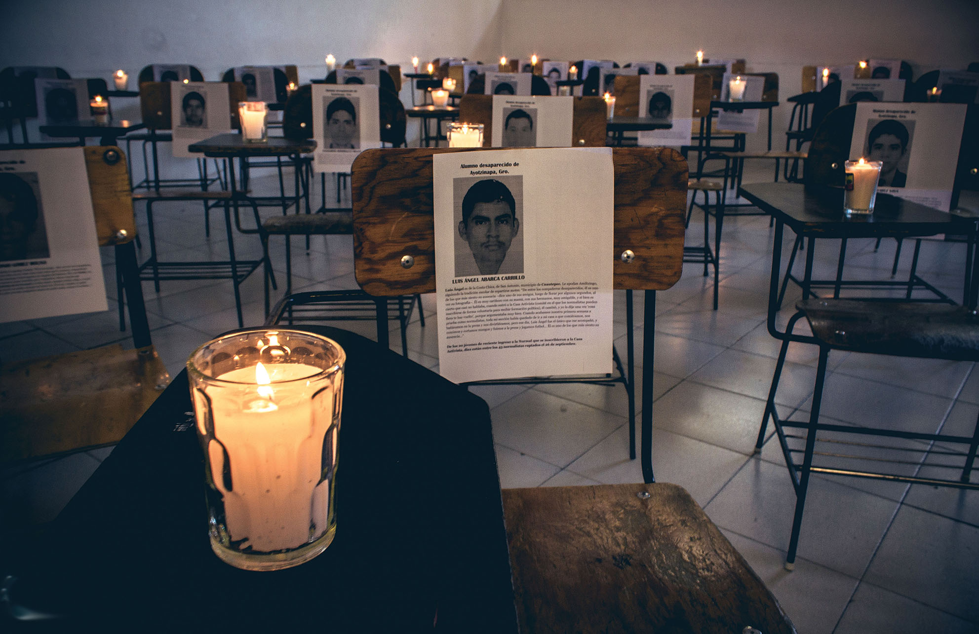 Candles sit on student desks in a memorial to the disappeared students in Ayotzinapa, 2015. (Photo by Uriel López.)