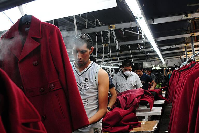 Men ironing women's red coats in Guatemala