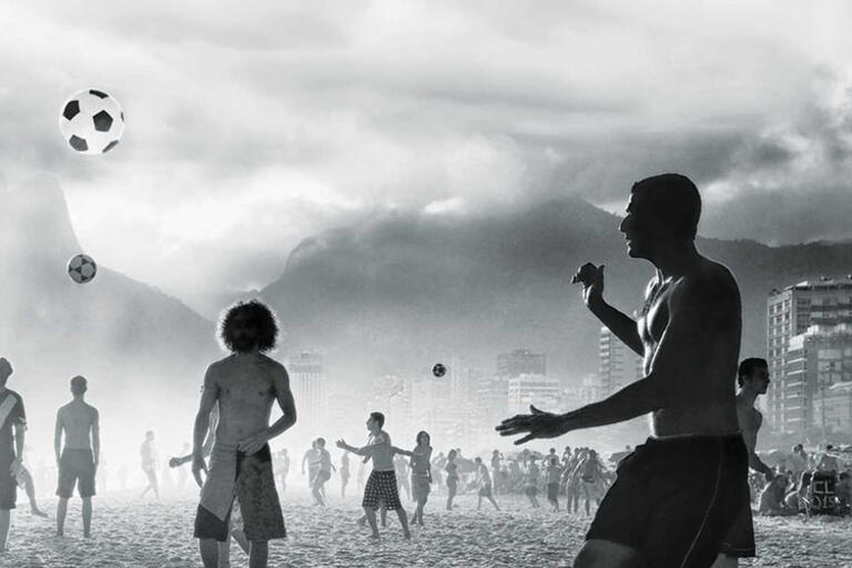 Black and white photo of people playing soccer at the beach in Rio de Janeiro 