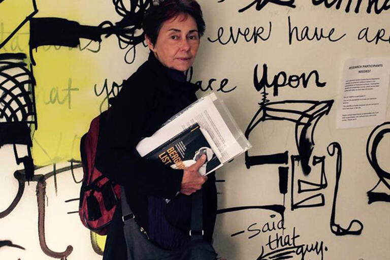 Nancy Scheper-Hughes standing up against a mural in Kroeber Hall