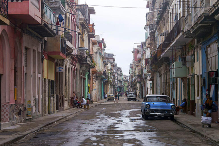 Havana street with old cars and people on the sidewalk