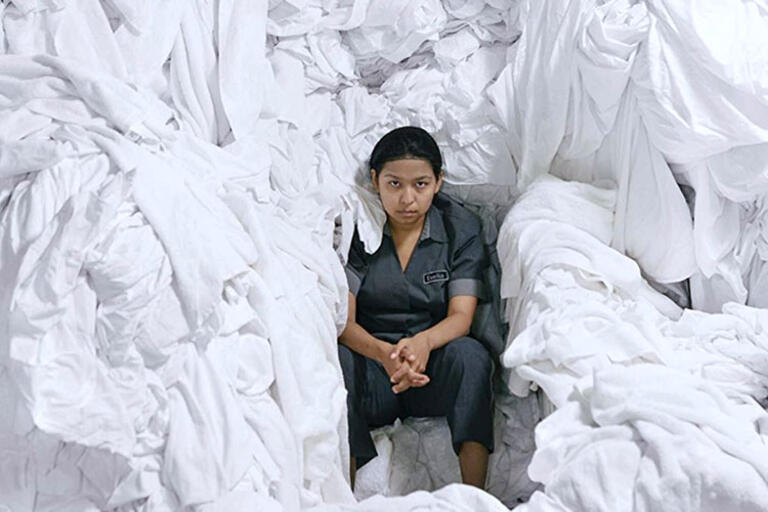 Woman seating surrounded by white bed sheets