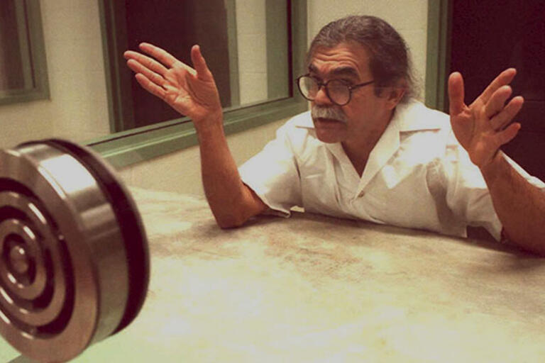 Oscar López Rivera behind a glass being interviewed before his release from prison