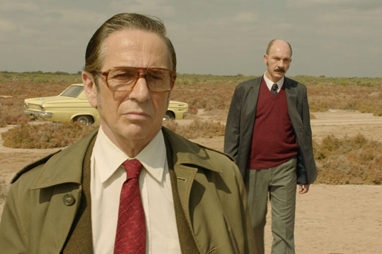 Still from the film Rojo, two men dress as detectives walking in the dessert 