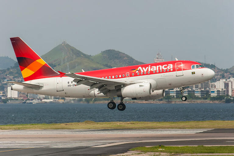 A red airplane with the word Avianca painted in white landing at Rio's Santos Dumont Airport