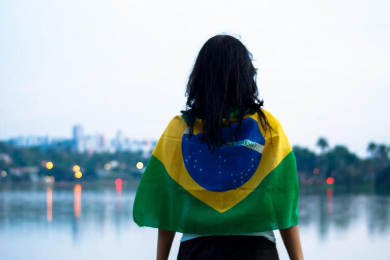 Woman wears a Brazilian flag and looks into the distance.