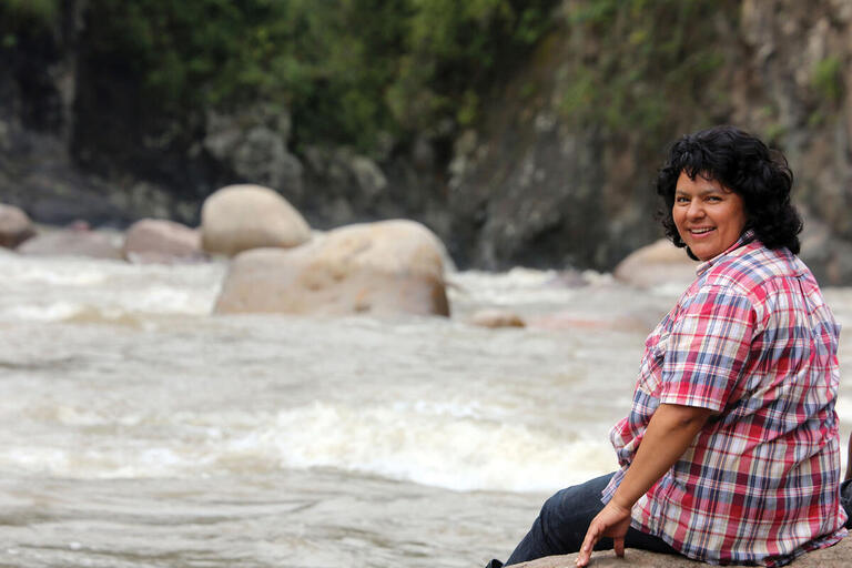Berta Cáceres sits on a rock in the middle of a river in the Río Blanco region of western Honduras in 2015. (Photo courtesy of the Goldman Environmental Prize.)