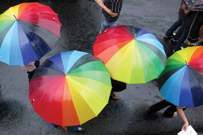 Marchers take shelter under rainbow umbrellas during a June 2010 gay pride parade in San Salvador. (Photo by Luis Romero/Associated Press.)