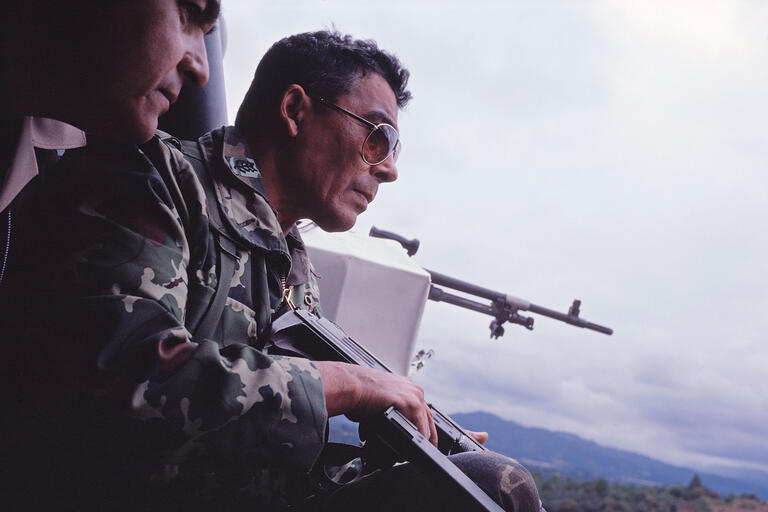 General Benedicto Lucas García, head of the Guatemalan Armed Forces, rides in a helicopter holding an assault rifle in 1982. (Photo by Susan Meiselas.)