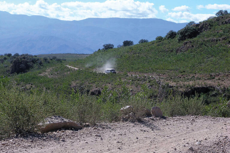 A lone bus kicks up a cloud of dust on a remote dirt road in the Mexican countryside. (Photo by Lon&Queta.)