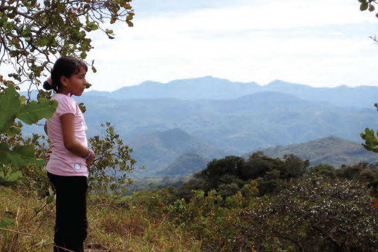 A young girl stands on a hilltop above the site of the El Mozote massacre. (Photo by Allison McKellar.)