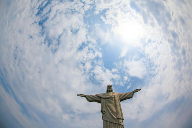 Rio de Janeiro’s Cristo Redentor statue outlined against a blue sky and swirling clouds. (Photo by Geraint Rowland.)
