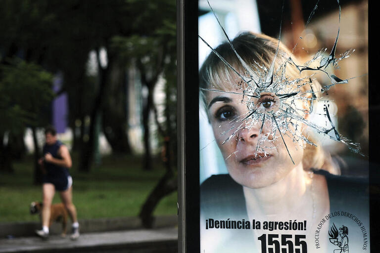 An ad featuring a woman's face with shattered glass centered on her eye urges Guatemalans to report domestic violence. (Photo by Orlando Sierra/AFP/Getty Images.)