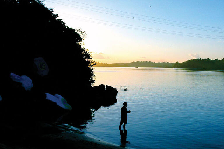 A man is silhouetted against the water as he fishes in the watershed of Belo Monte, site of a controversial dam project in Brazil.. (Photo by Bruno Abreu.)
