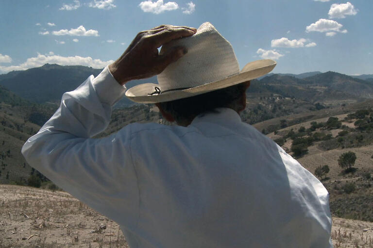 Pascual, shown from the back against a Mexican landscape and featured in “Those Who Remain,” lives with his wife  in a remote region of Puebla and has three children in the United States. (Photo courtesy of Fundación BBVA Bancomer.)