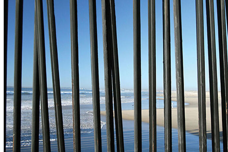 Vertical steel posts extending from the beach into the Pacific Ocean form the border between Tijuana and San Diego. (Photo by Nathan Gibbs.)