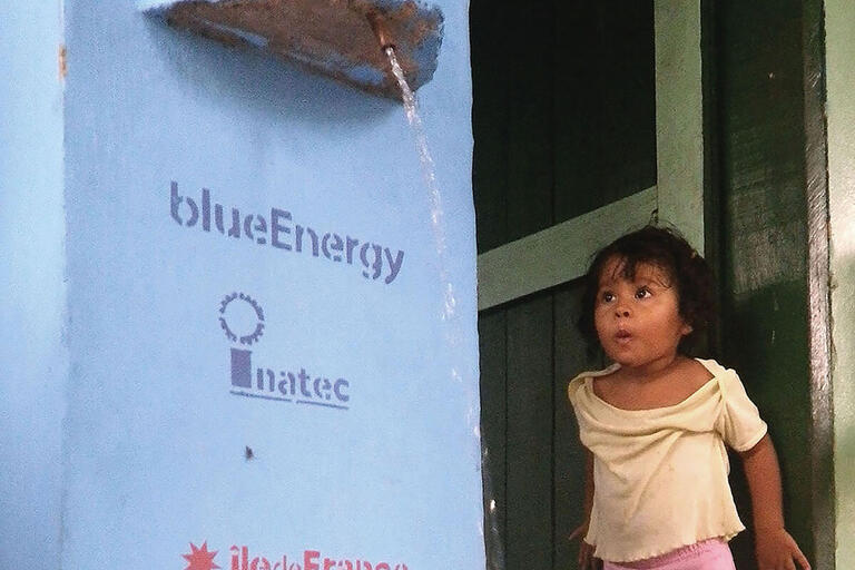  A young girl watches a water filtration unit in action. (Photo courtesy of blueEnergy.)