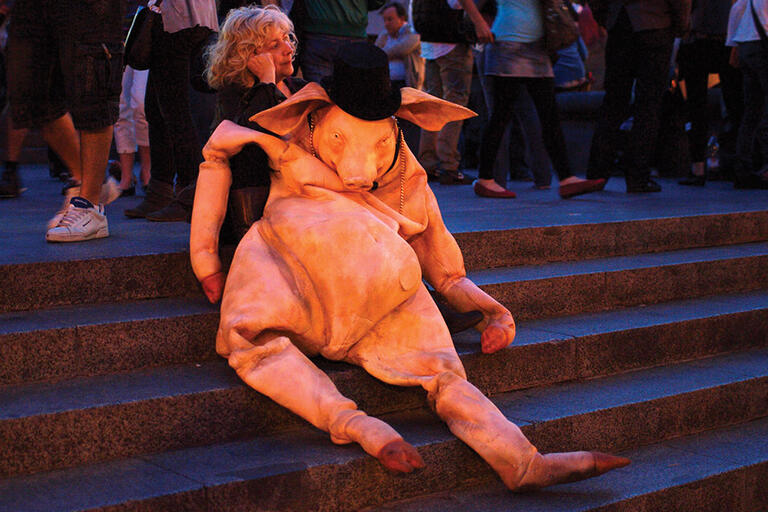A woman sitting on steps and carrying a fake pig at a protest against neoliberalism. (Photo by Vicnaba.)