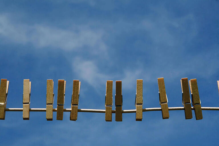 Pegs hang on a clothesline against a blue sky with scattered clouds. (Photo by MollyBob.)
