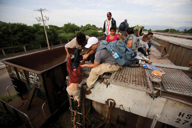Migrants in Ixtepec, Mexico, climb on top of the freight train “La Bestia” in 2014. (Photo by Eduardo Verdugo/Associated Press.)
