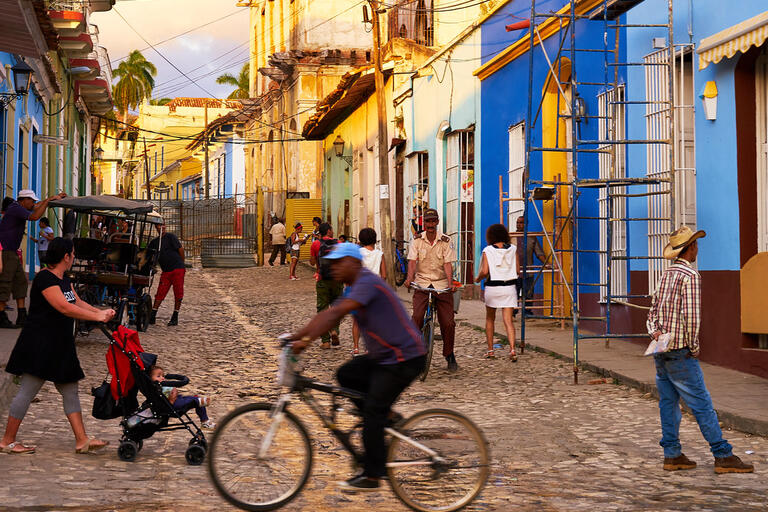 Street scene, people walking and biking in front of colorful buildings