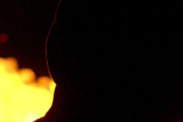 A man silhouetted against flames, from "Sin señas particulares."