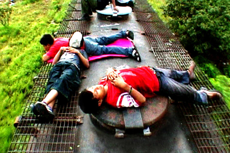 Children lie on top of a train as it moves through the countryside