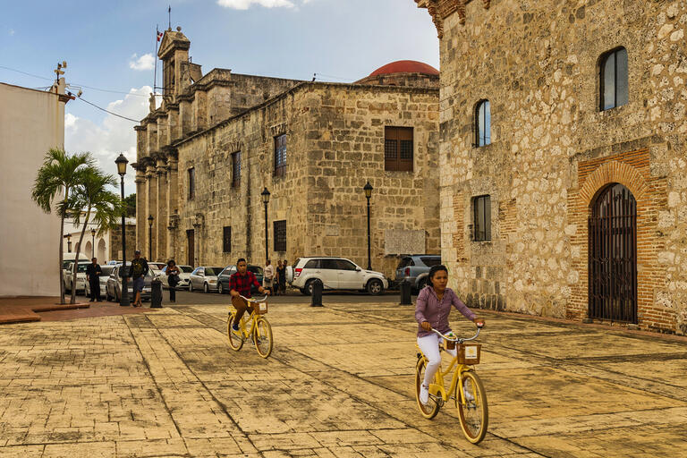 Two people ride bikes through Santo Domingo