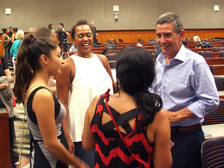 Professor Raymond Telles in conversation with three female students