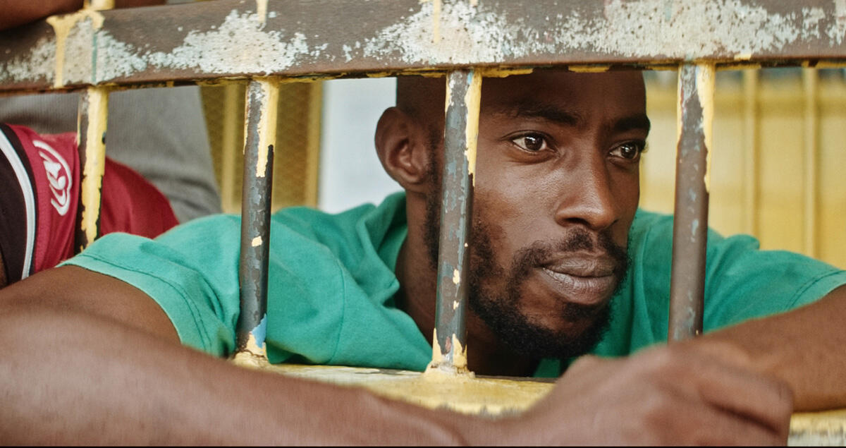 Still from Carpinteros. A man looks through bars.