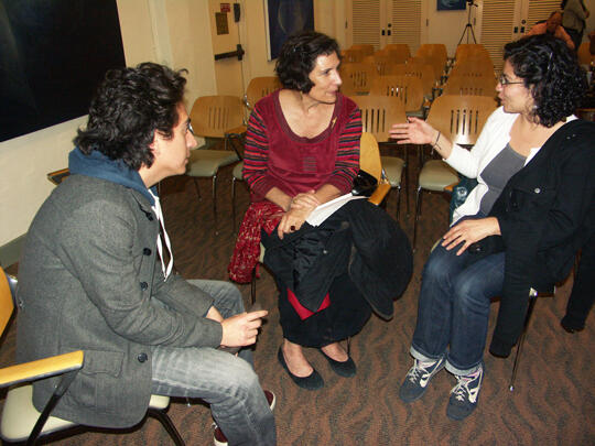 The speaker is in conversation with two event attendees while sitting in a circle formation.