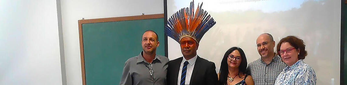 Five people, one in an Indigenous headdress, the rest are his examining committee for a master's degree.