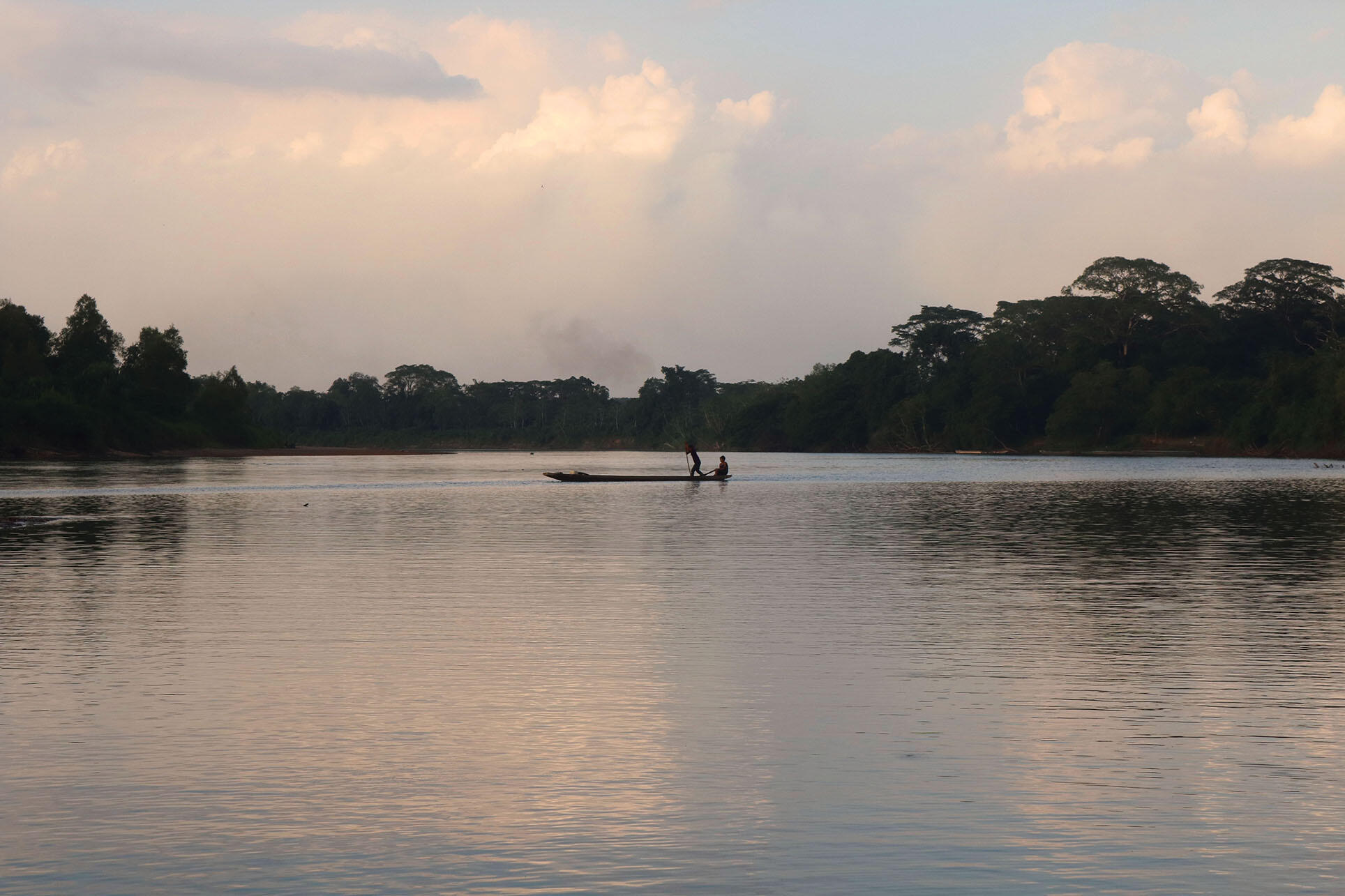 A boat with two men crosses the calm waters of Río Patuca in an indigenous bioreserve in Honduras.  (Photo by Marcio Martínez.)