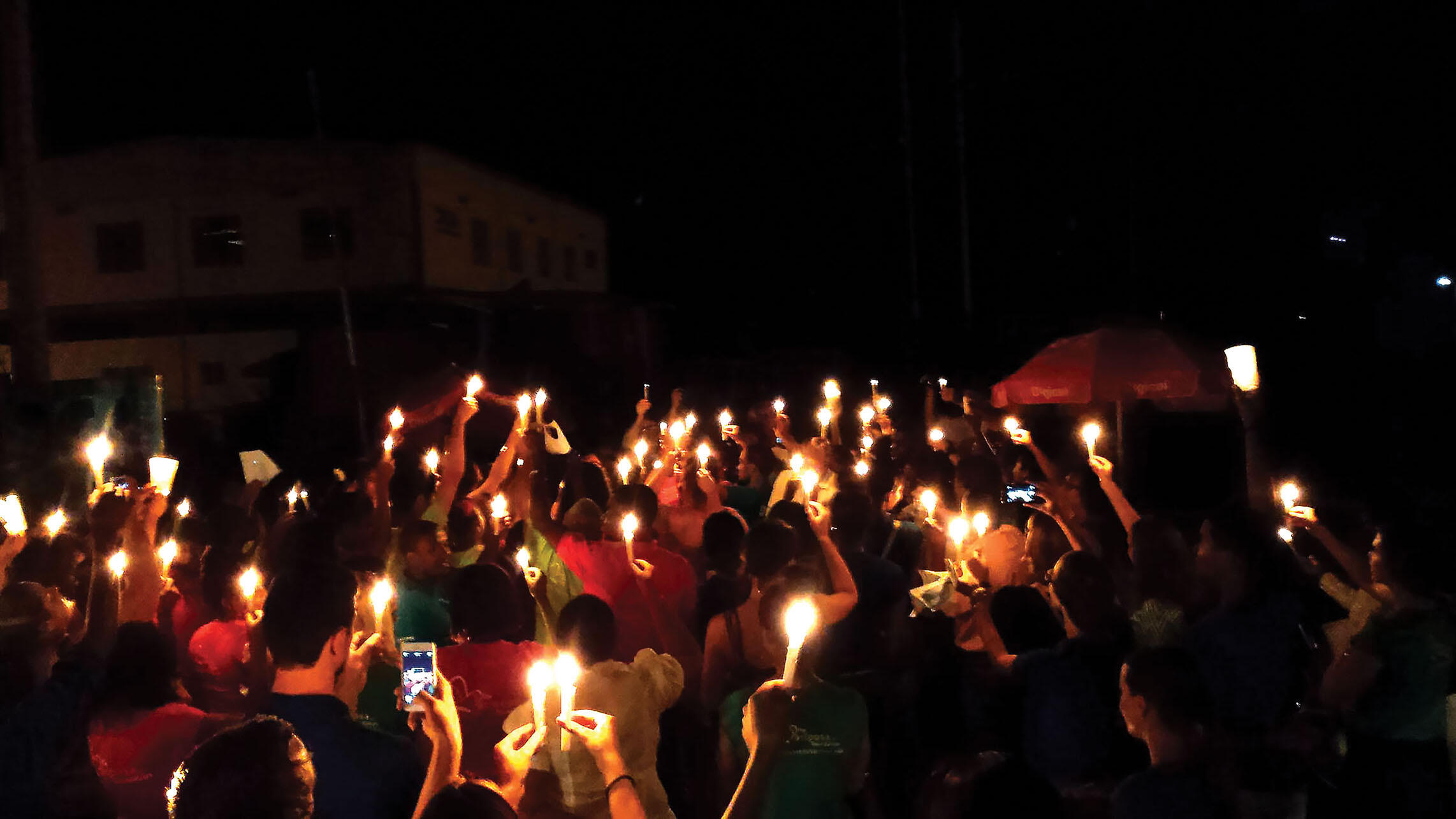 A candlelit procession for a Border of Lights commemoration marches toward the river crossing in Dajabón. (Photo by Edward Paulino.)