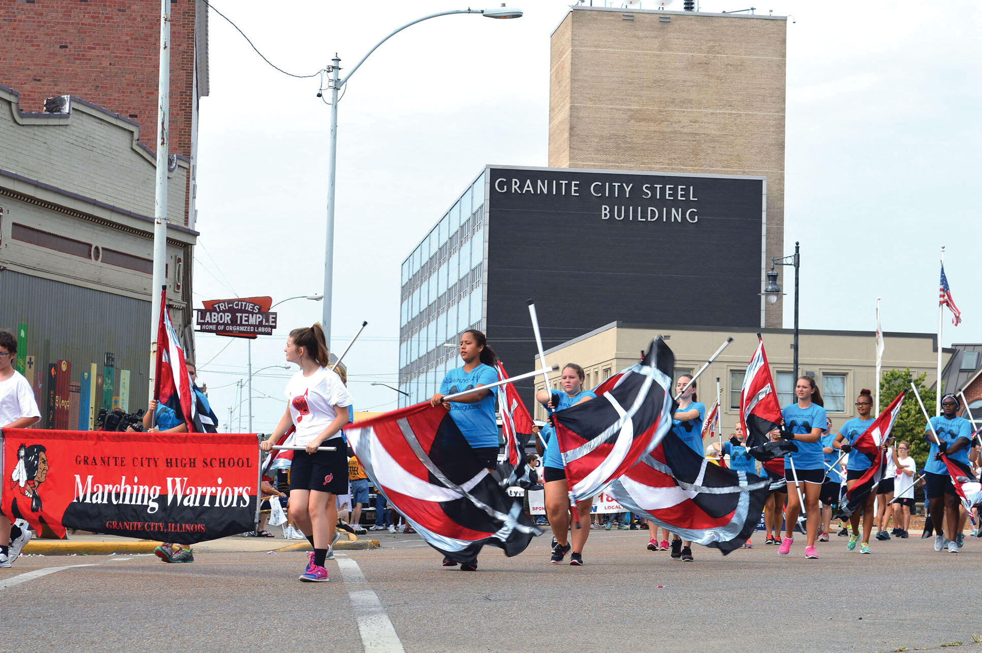A color guard with flags but no uniforms marches in the 2015 Labor Day parade past the local union hall and the Granite City Steel Building. (Photo by Doug May.)