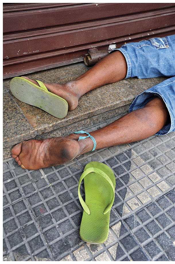  “Every shoe was engrained with the story of the feet that used them, engrained with the dirt of the roads they had traveled.” The sandals of a man lying in the street,  Rua Líbero Badaró, São Paulo.(Photo by Jurandir Lima.)