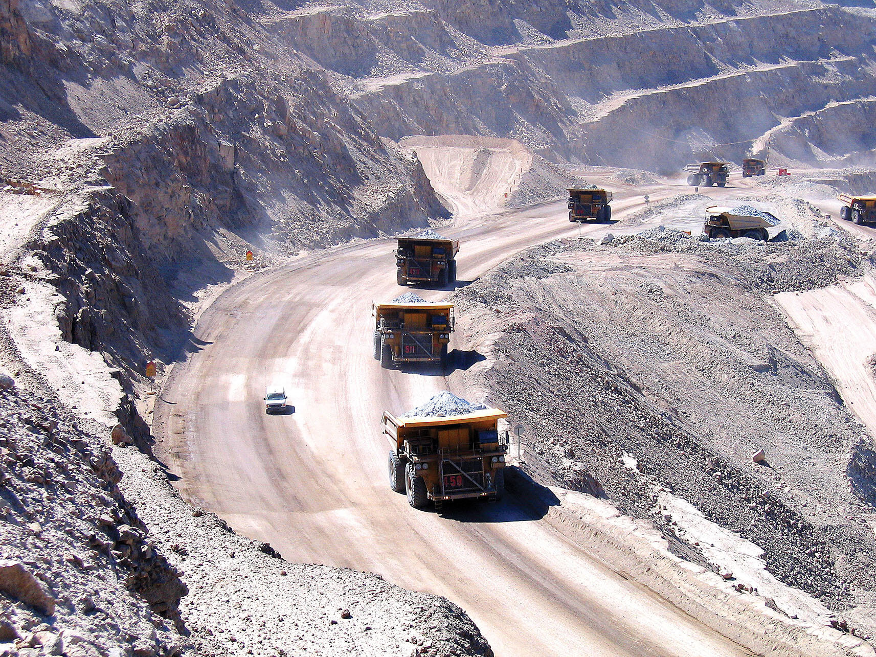 Large dumptrucks full of raw ore trundle up the dusty ramps of Chile’s Chuquicamata copper mine. (Photo by Magnus von Koeller.)