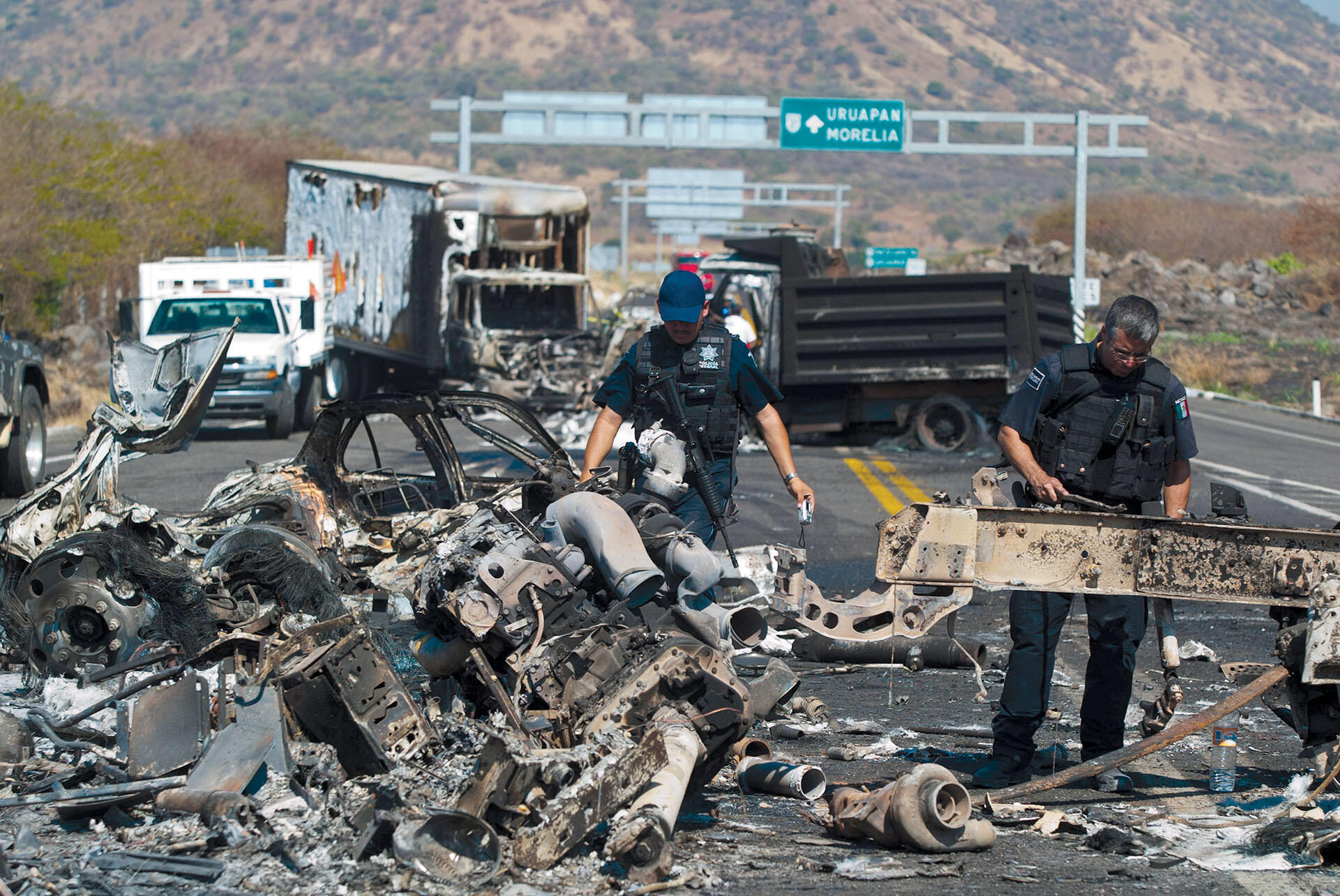 Bullet-ridden and burned-out vehicles line the road in the aftermath of a battle between the Mexican federal police and the La Familia Michoacana cartel in Apatzingán, Michoacán. (Photo by Fernando Castillo/LatinContent/Getty Images.)