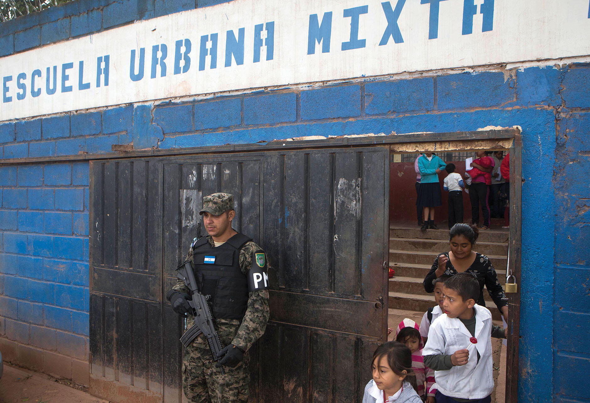 A member of the Honduran Military Police stands guard at the entrance of a school. (Photo by Esteban Félix/AP Photo.)