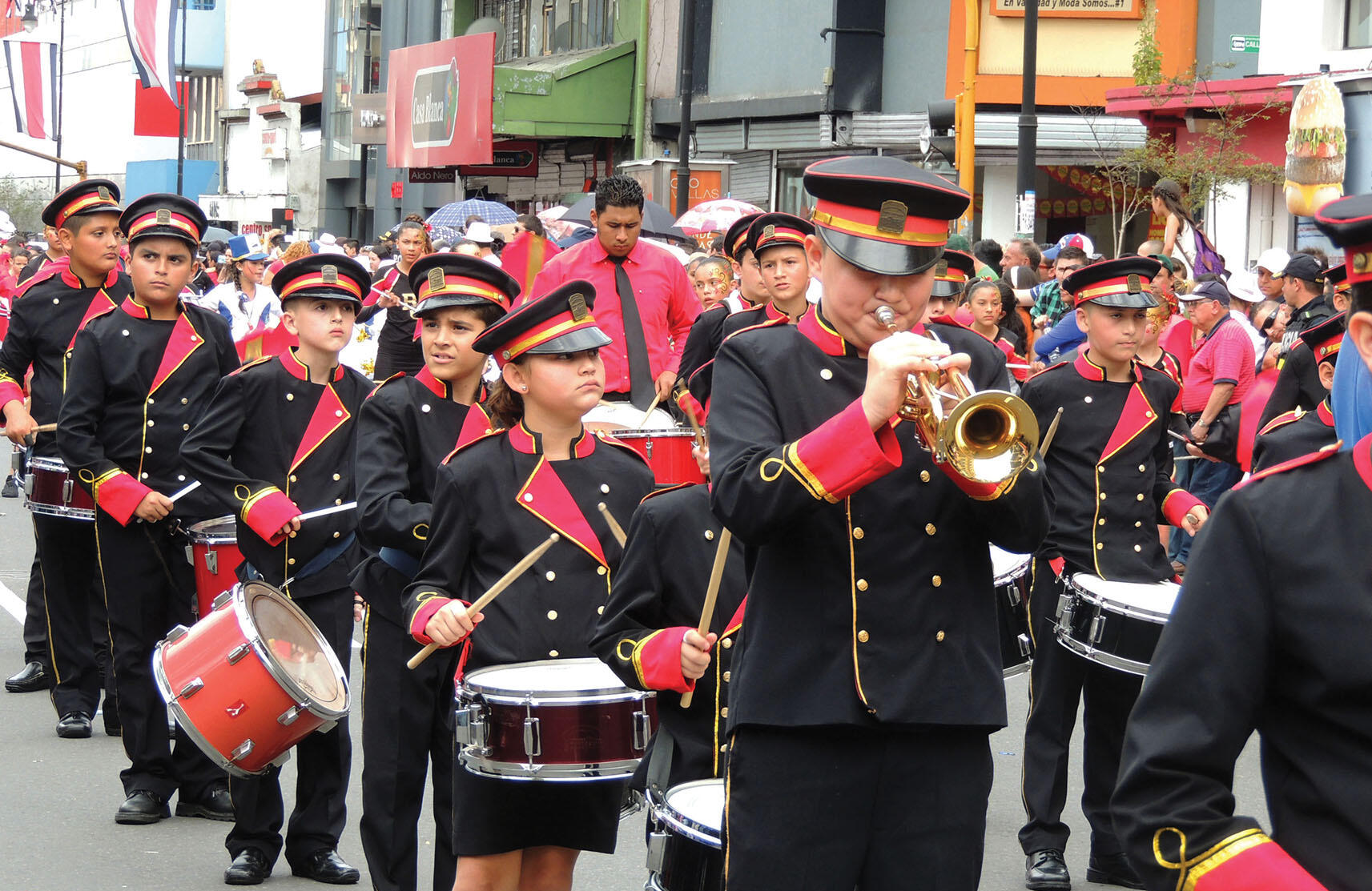 A children’s marching band plays and marches down a street in Costa Rica. (Photo by MadriCR.)