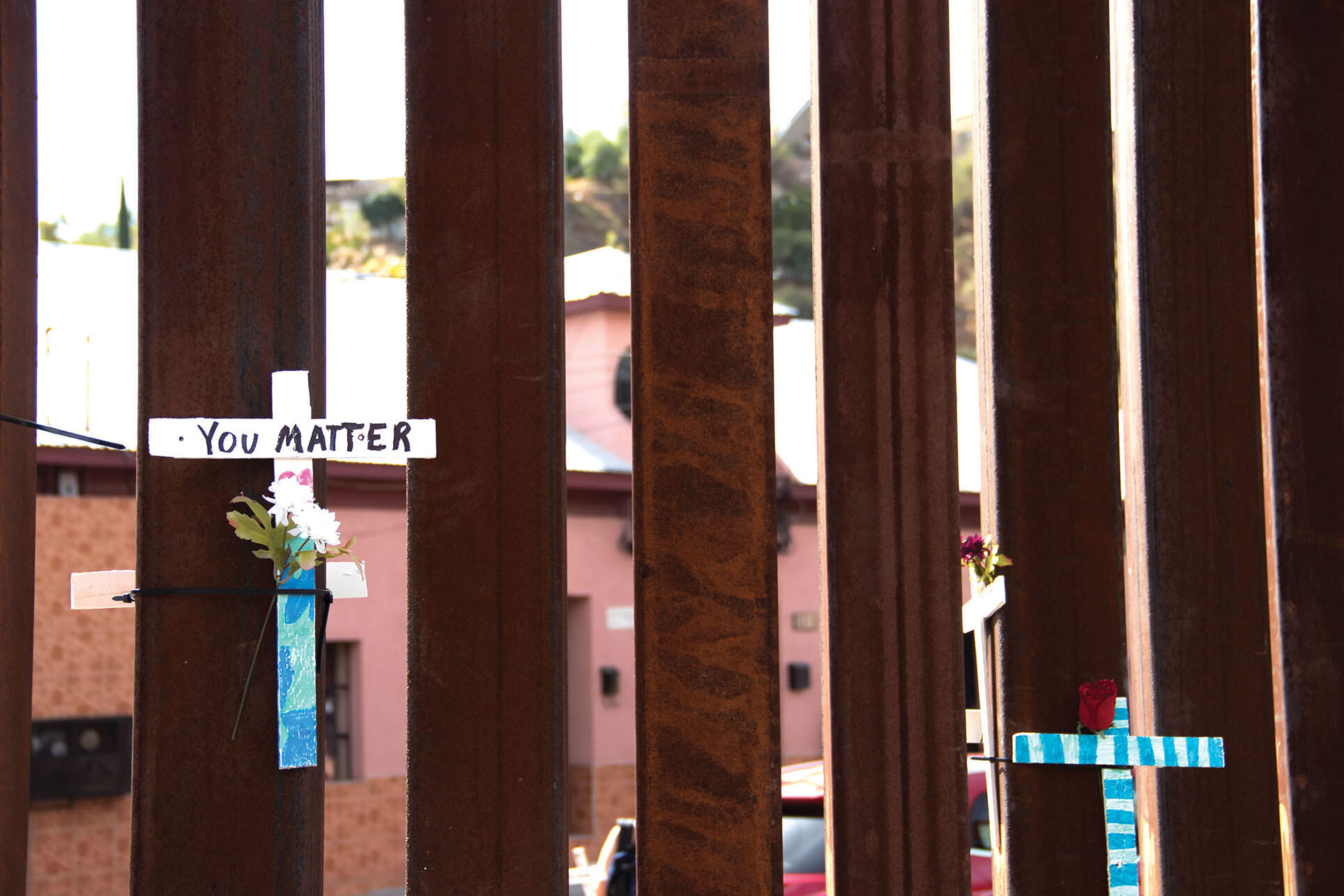 Crosses are hung on the metal U.S.–Mexico border fence in Nogales. (Photo by Peg Hunter.)