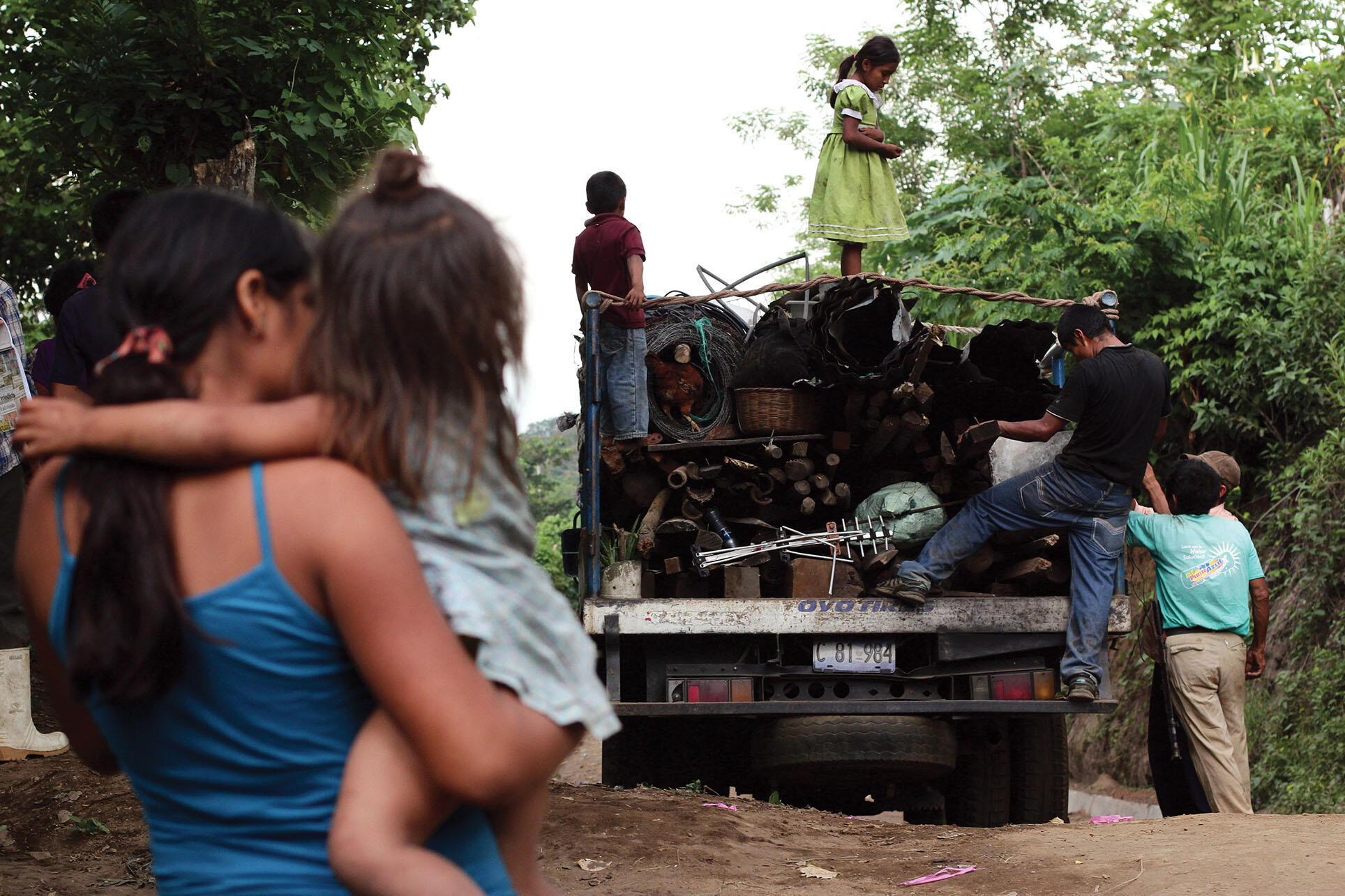 A woman watches neighbors loading possessions on a truck as they flee their homes following gang threats in Tunamiles, El Salvador. (Photo by Salvador Melendez/AP Photo.)