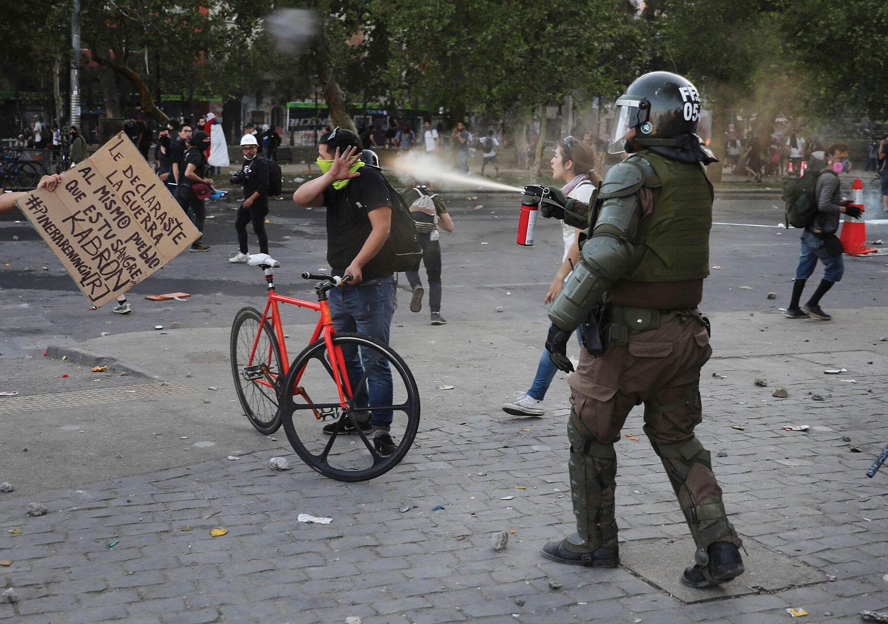 A Chilean carabinero pepper-sprays a demonstrator in Santiago, October 2019. (Photo by Rodrigo Abd/AP Photo.)
