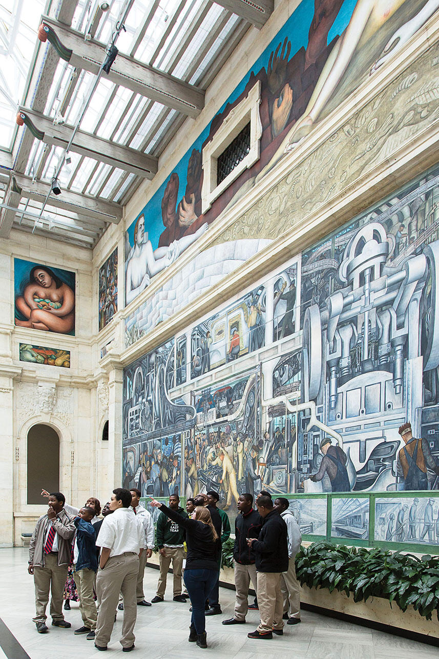 A docent points out parts of “Detroit Industry” to local students visiting the Detroit Institute of Art’s Rivera Court. (Photo © 2017 Detroit Institute of Arts.)