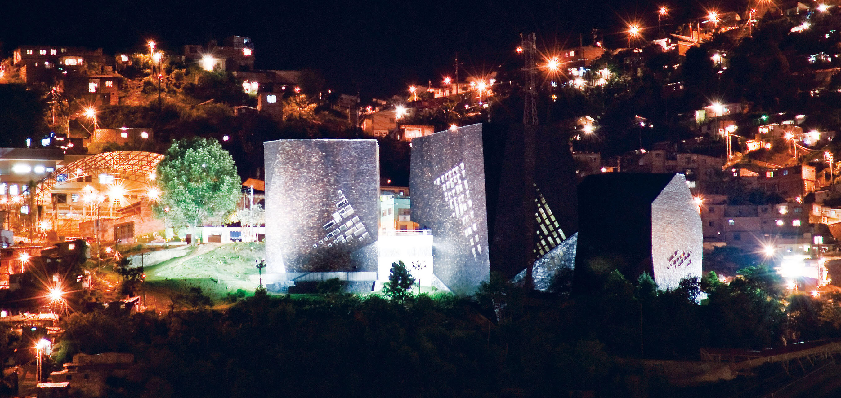 A huge library, shown at night on a hillside in a poor neighborhood of Medellín, Colombia, creates a safe public space. (Photo by Daniel Echeverri.)