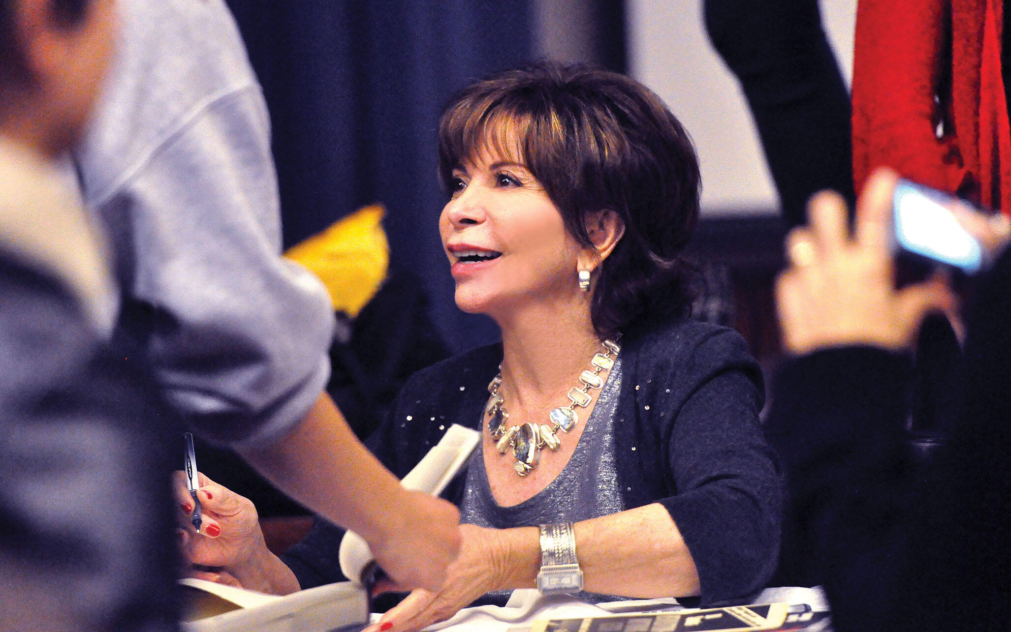 Isabel Allende looks up at an audience member as she signs copies of "Maya's Notebook" at UC Berkeley. (Photo by Peg Skorpinski.)